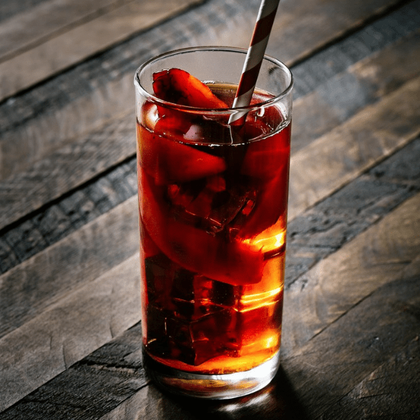 Chilled beverage with ice and fruit slices in a glass, set on a rustic wooden table.