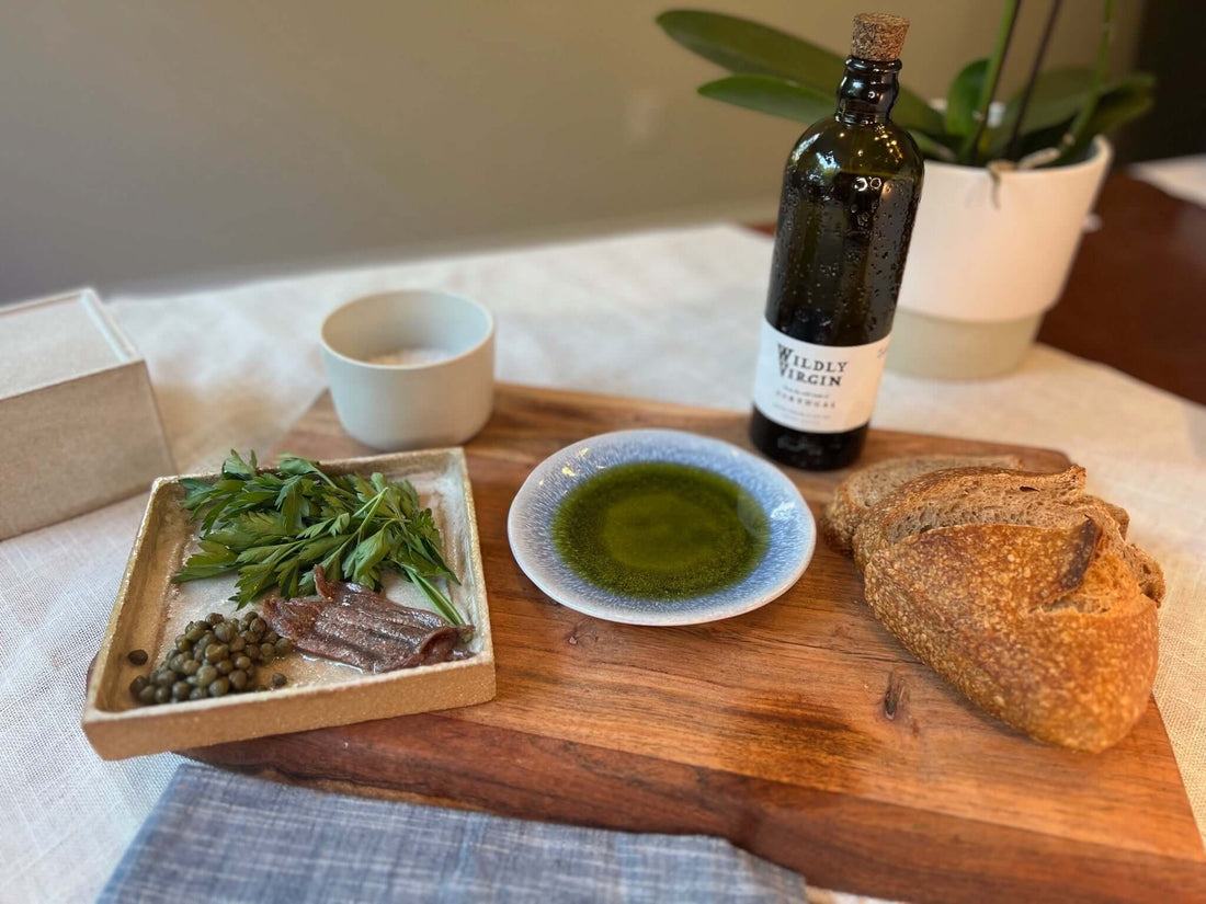 a dish of olive oil with anchovies and capers and bread