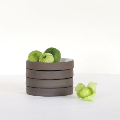 Handcrafted ceramic bowl stack with green decorative fruits on a neutral background.
