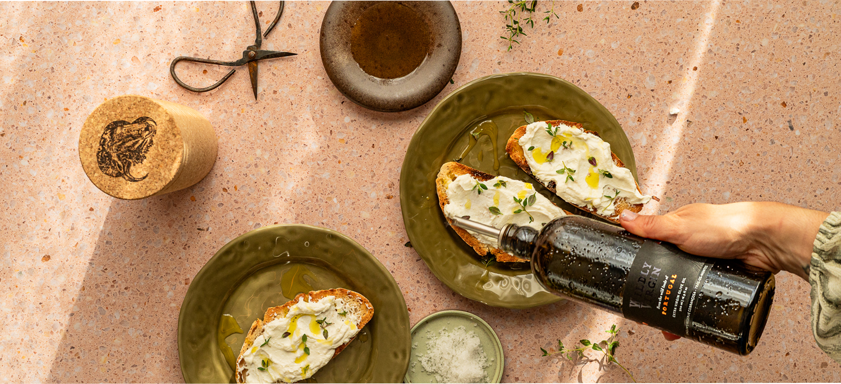 Person spreading ricotta on bread and drizzling olive oil