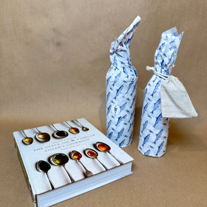 Foodie gift set with two wrapped olive oil bottles and the Olive Oil & Vinegar Lover's Cookbook on a brown background.