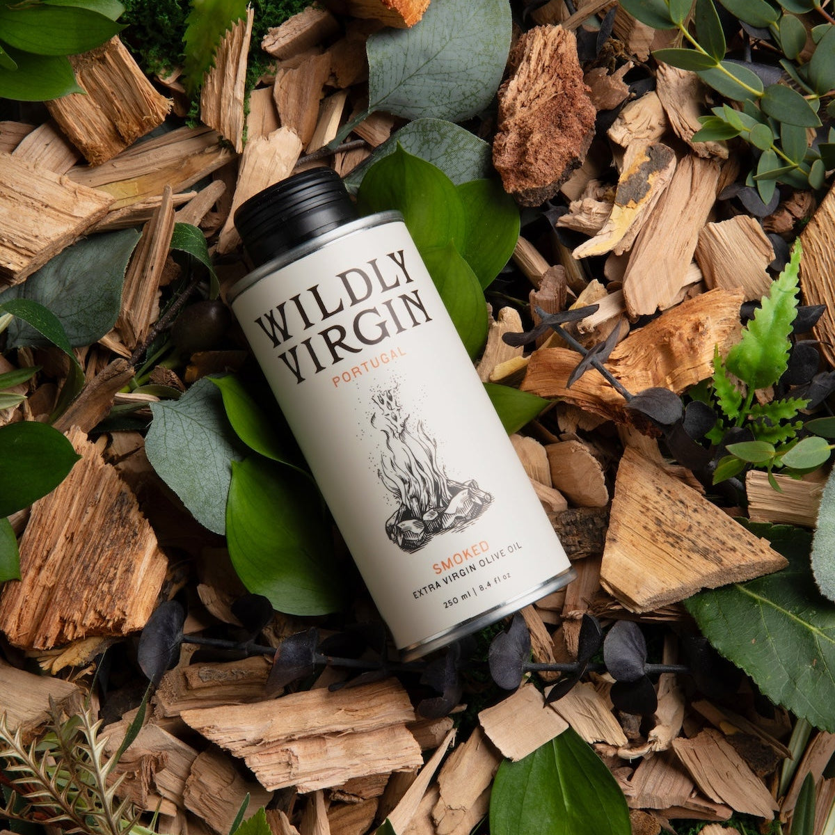 A can of Wildly Virgin Smoked Meats smoked apple pie sauce, nestled in a natural arrangement of wood chips, green leaves, and moss.