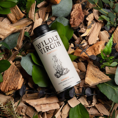 A can of Wildly Virgin Smoked Meats smoked apple pie sauce, nestled in a natural arrangement of wood chips, green leaves, and moss.