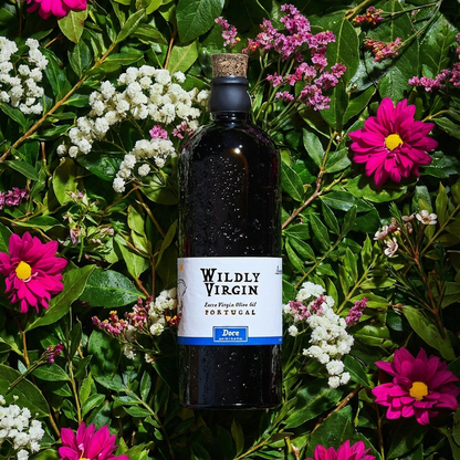 A bottle of Doce extra virgin olive oil surrounded by colorful flowers, showcasing its fruity and smooth qualities.