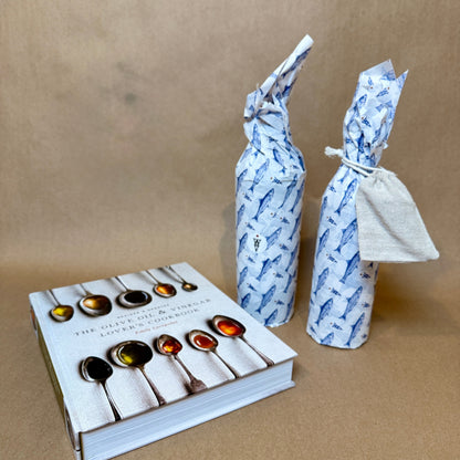 Foodie gift set with two wrapped olive oil bottles and the Olive Oil & Vinegar Lover's Cookbook on a brown background.