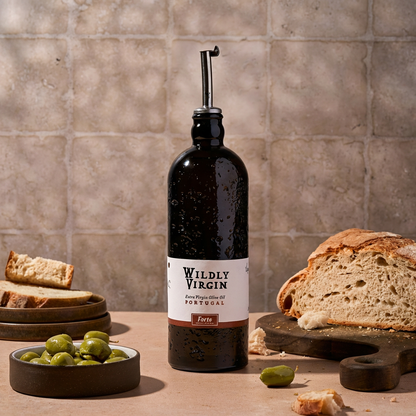 Forte olive oil bottle by Wildly Virgin with bread and olives on a rustic table.