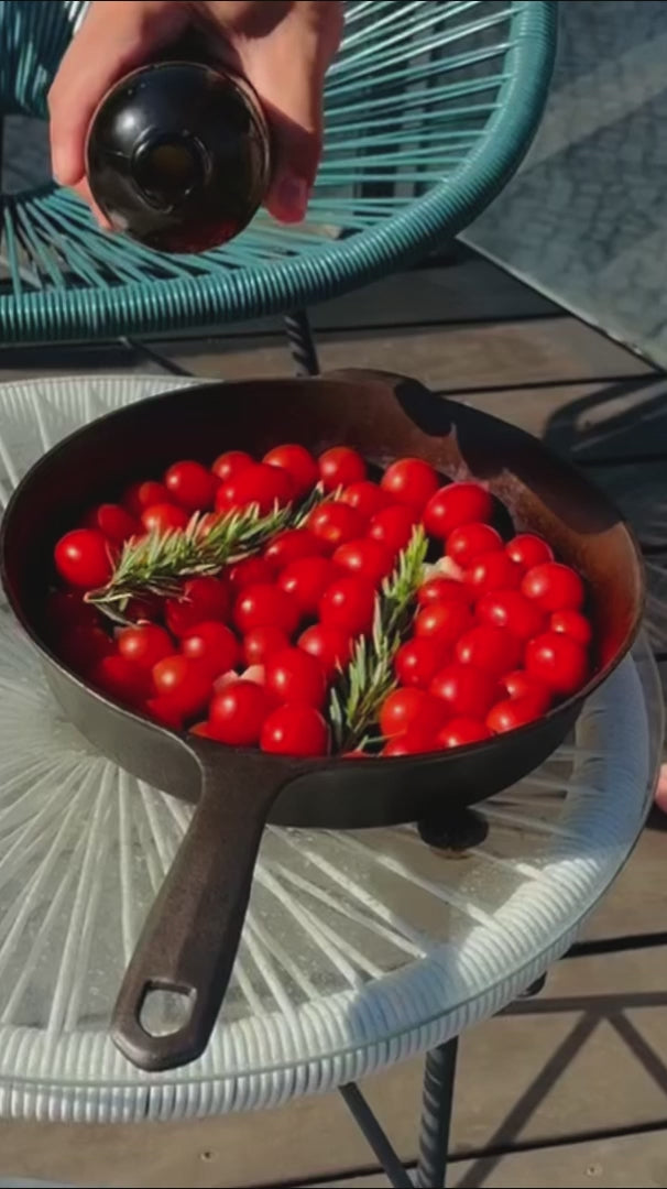 Wildly Virgin olive oil being poured over tomatoes and rosemary