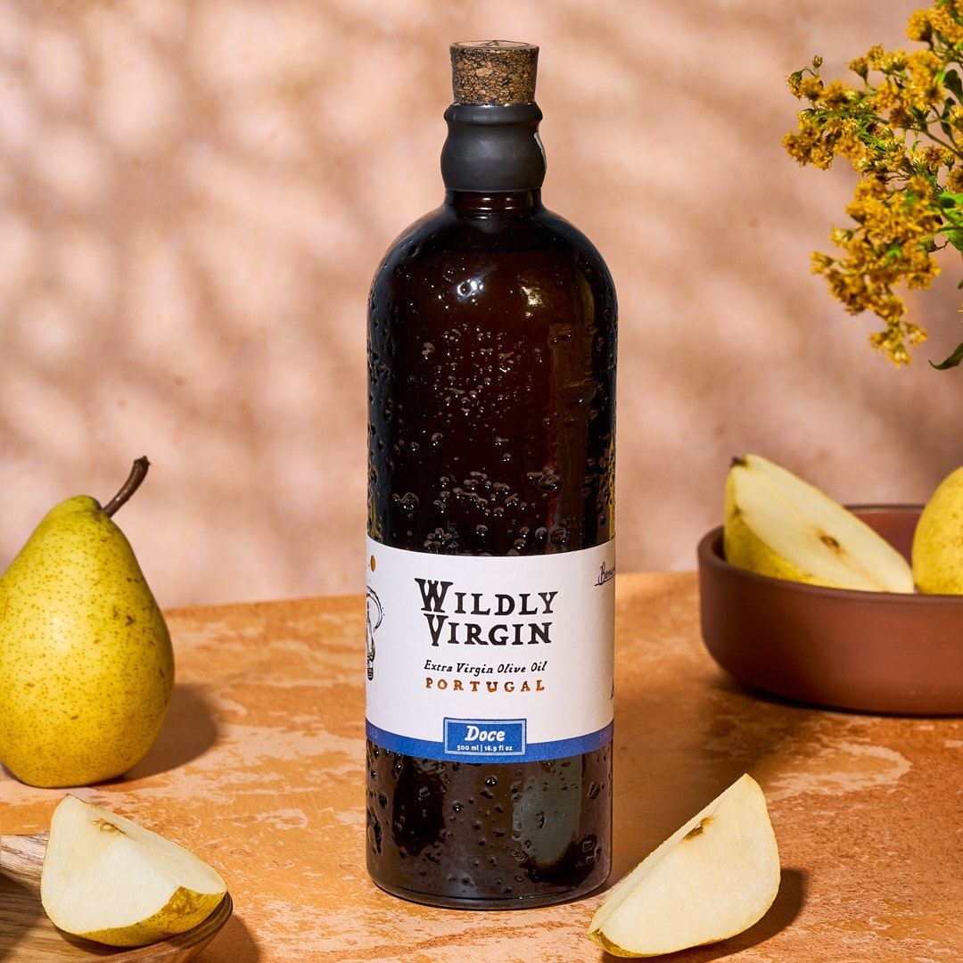 Doce extra virgin olive oil from Portugal in a decorative bottle, surrounded by fresh pears and flowers.